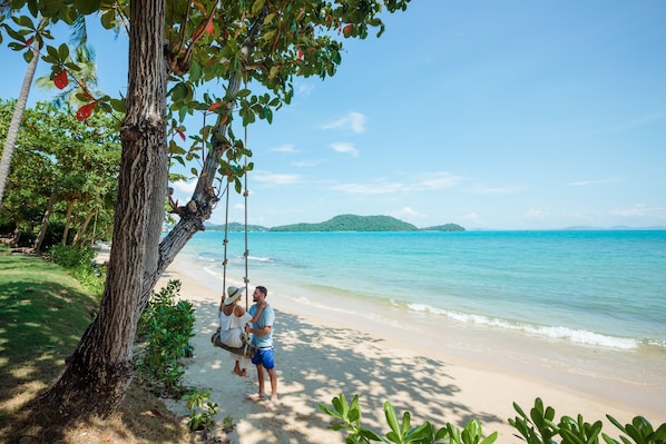 Pantai pribadi, pasir putih, kursi berjemur, dan payung pantai