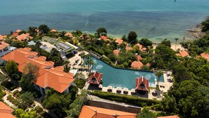 A resort with a large swimming pool, multiple buildings with red roofs, and a beach area. - Amatara Welleisure Resort (Wichit)