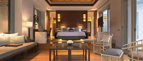 A spacious room with a large bed, a sofa, and a dining table.