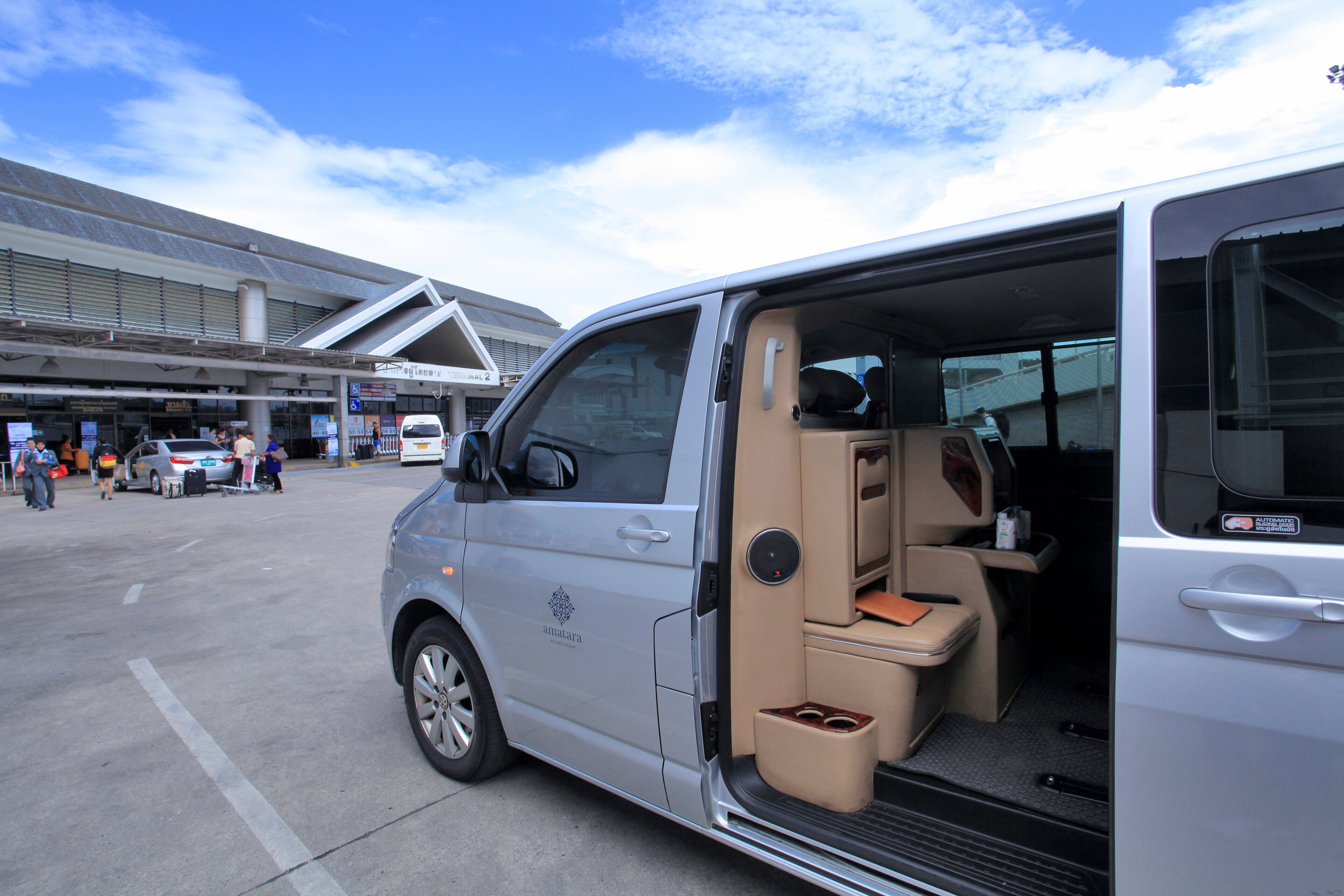 A van with an open door, revealing a spacious interior with a bench seat and a small table.