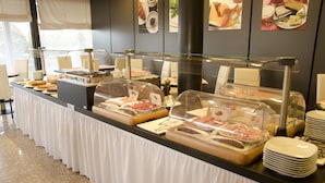 Ein reichhaltiges Buffet mit verschiedenen Speisen in klaren Behältern, einer weißen Tischdecke und einer Glasvitrine.