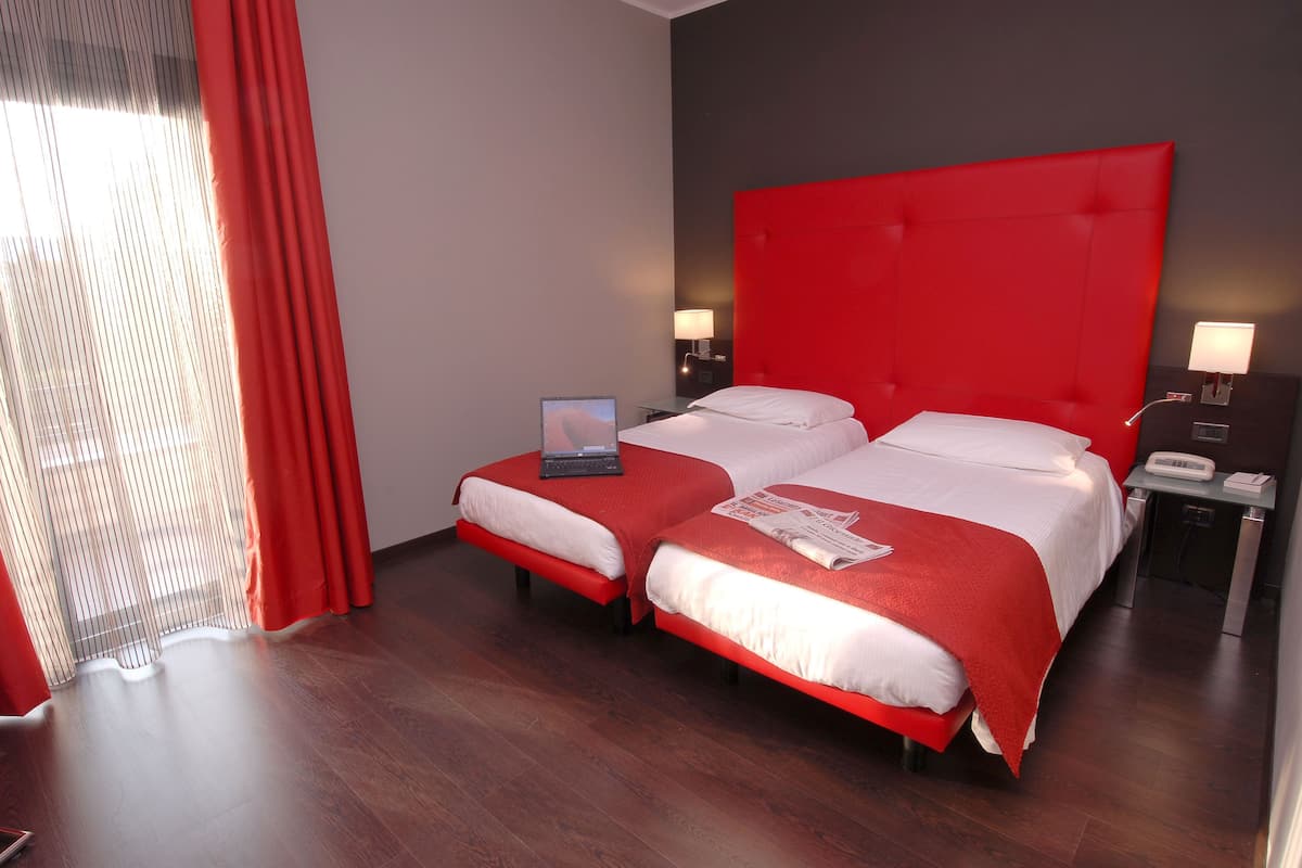 A hotel room with two beds, a laptop on one bed, and a telephone on the nightstand.