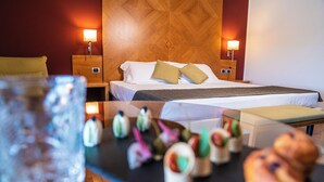 Ein Hotelzimmer mit einem Bett, Nachttischlampen, einem Nachttisch und einem Tisch mit Gebäck.