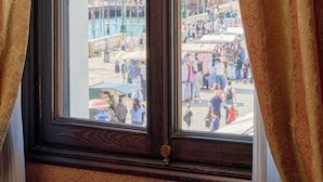 Una ventana con vistas a un edificio histórico con cúpula, un paseo marítimo y gente caminando.