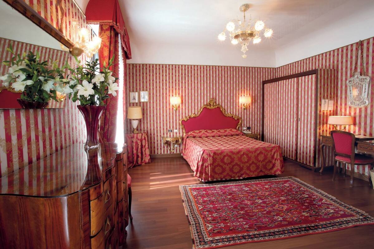 Una habitación con una cama grande, un aparador, un escritorio y una silla.
