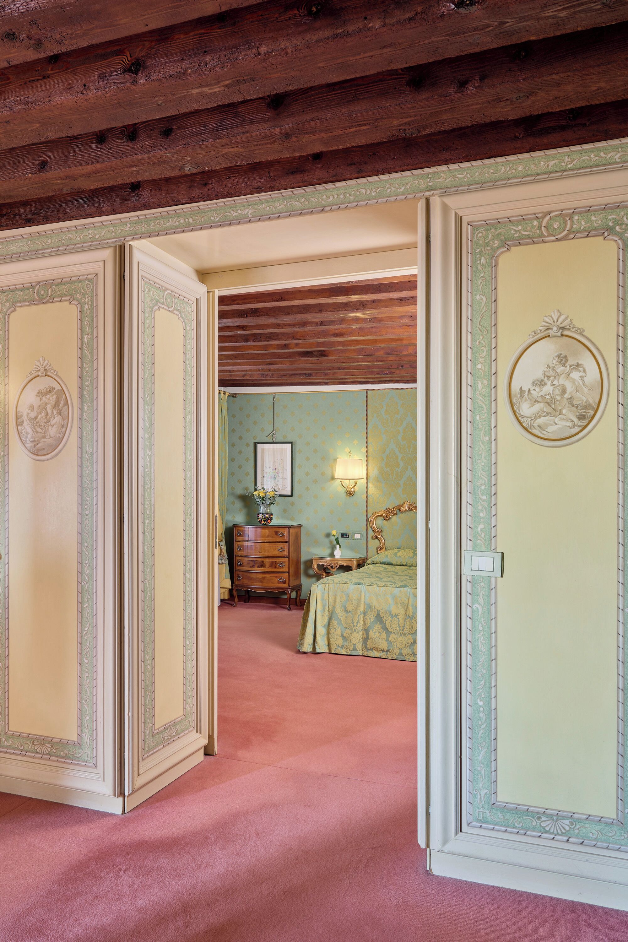 A room with a bed, a dresser, and a wall-mounted lamp.