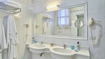 A bathroom with two sinks, a large mirror, a towel rack, and a hairdryer.