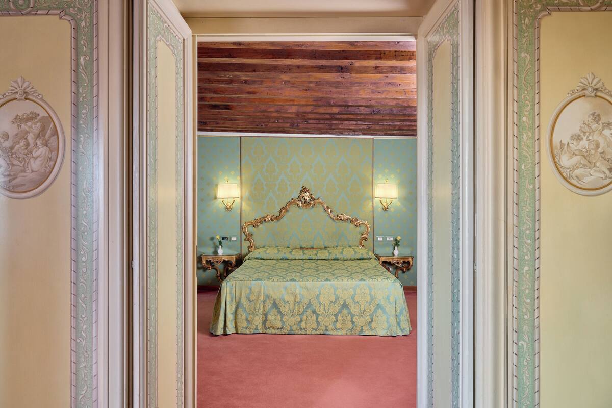 Un dormitorio con una cama grande, dos mesitas de noche y un espejo sobre la cama.