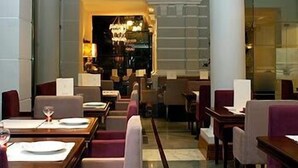 Un hall de hotel con una zona de estar central, una recepción y una escalera que lleva a un piso superior.