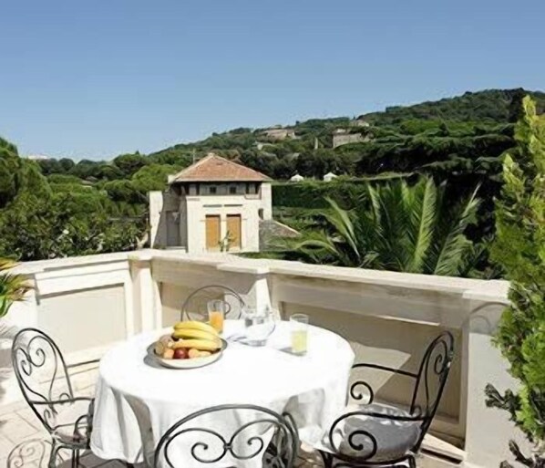 Une table ronde recouverte d’une nappe blanche, deux chaises et une assiette de fruits.