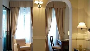 Una habitación de hotel con una cama, dos sillas, un escritorio y dos lámparas.