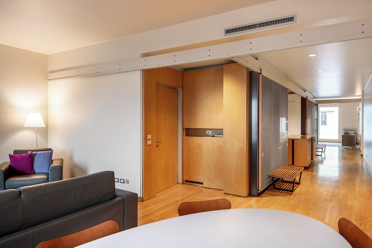 A modern hotel room with a sofa, a table, and a wooden partition wall.