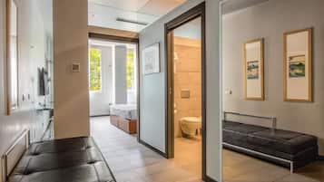 Ein modernes Hotelzimmer mit großem Bett, einer Sitzecke, einem Badezimmer und Kunstwerken an den Wänden.