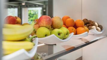 Ein Buffet mit verschiedenen Früchten, darunter Äpfel, Orangen und Bananen.