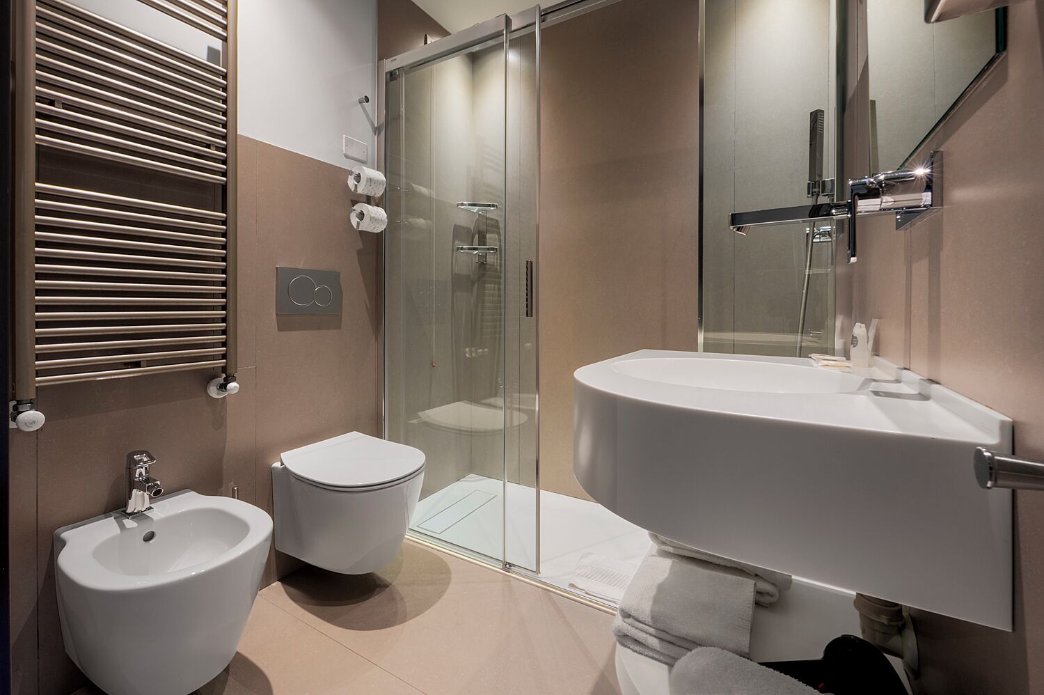 A modern bathroom with a bidet, toilet, and a large sink.