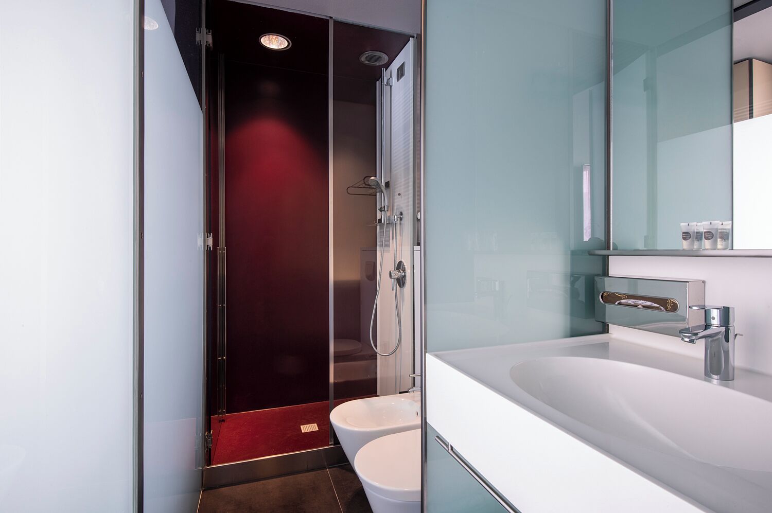 A modern bathroom with a glass shower enclosure, a white sink, and a mirror above the sink.
