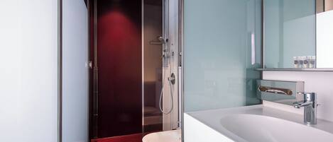 A modern bathroom with a glass shower enclosure, a white sink, and a mirror above the sink.
