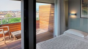 A hotel room with a balcony, a bed, a chair, and a view of the city. - Hotel Verona (Verona)