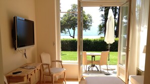 Quarto de hotel com televisão, mesa de trabalho, cadeira, cama e vista para o exterior.
