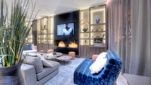 A modern living room with a flat-screen TV, a fireplace, and a blue sofa. - Best Western Plus Nice Cosy Hôtel (Nice)