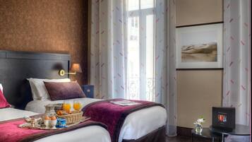 Una camera d'albergo con due letti, un vassoio per la colazione, una TV e una finestra con tende.