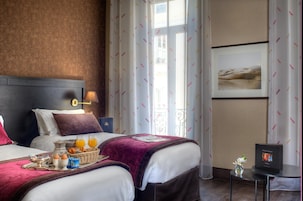 Ein Hotelzimmer mit zwei Betten, einem Frühstückswagen, einem Fernseher und einem Fenster mit Vorhängen.