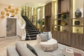 A modern interior with a staircase, a sofa set, and a bookshelf with decorative items. - Best Western Plus Hotel Cosy Nice (Nice)