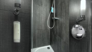 Un baño moderno con un espejo grande, ducha integrada y lavamanos blanco.