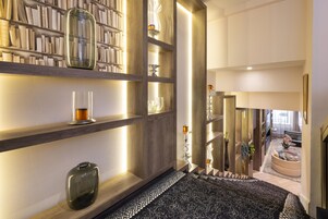 Et moderne interiør med træhylder, et tæppe med mønster og udsigt til et opholdsområde med sofa og planter.