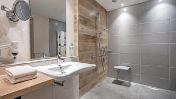 Un baño moderno con una pared de acento de madera, un espejo grande, un lavabo y una zona de ducha.