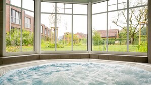 Un bain à remous avec vue sur un jardin et des bâtiments.