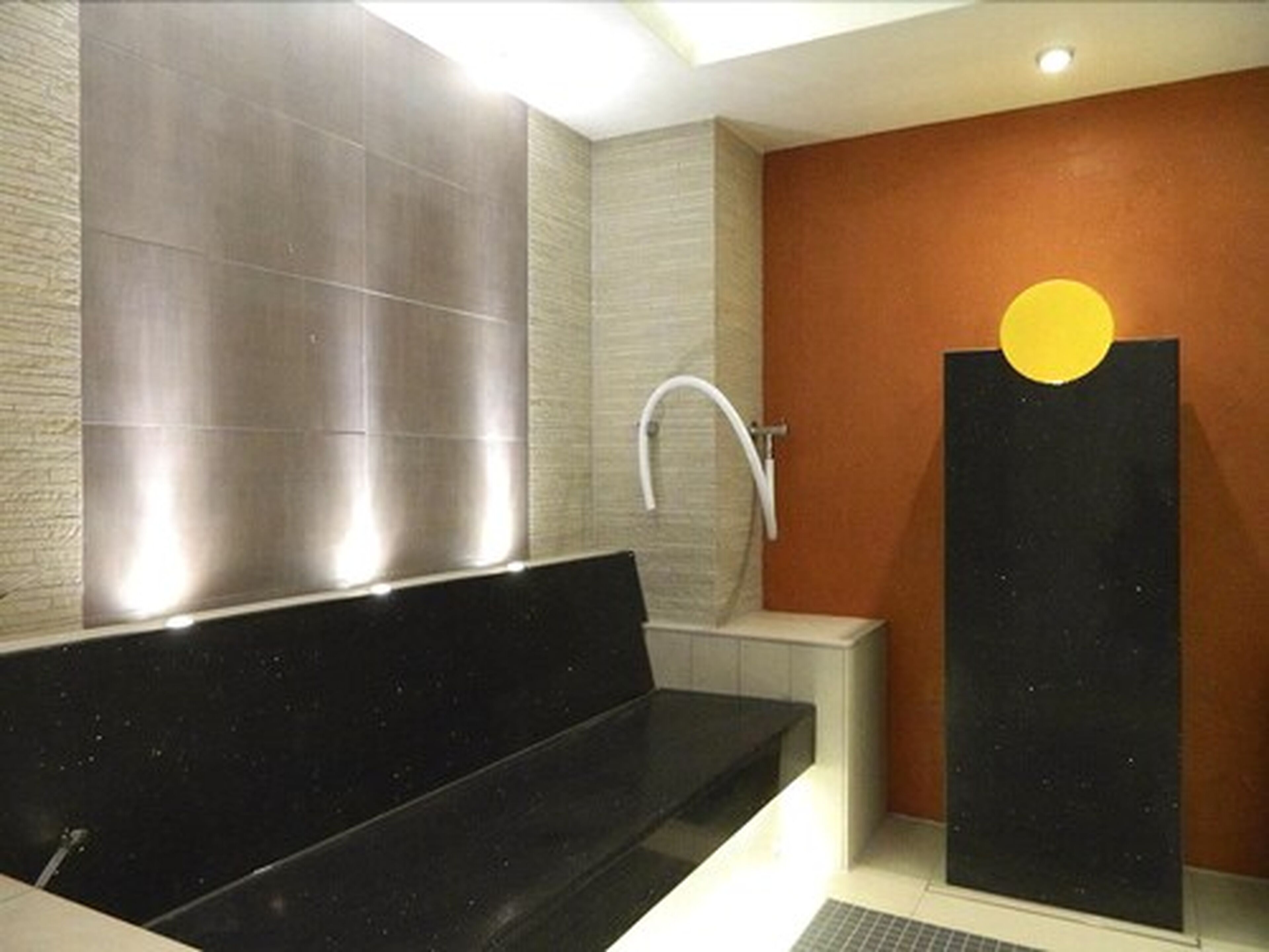 Un baño moderno con una bañera negra, un lavabo blanco y una zona de ducha.