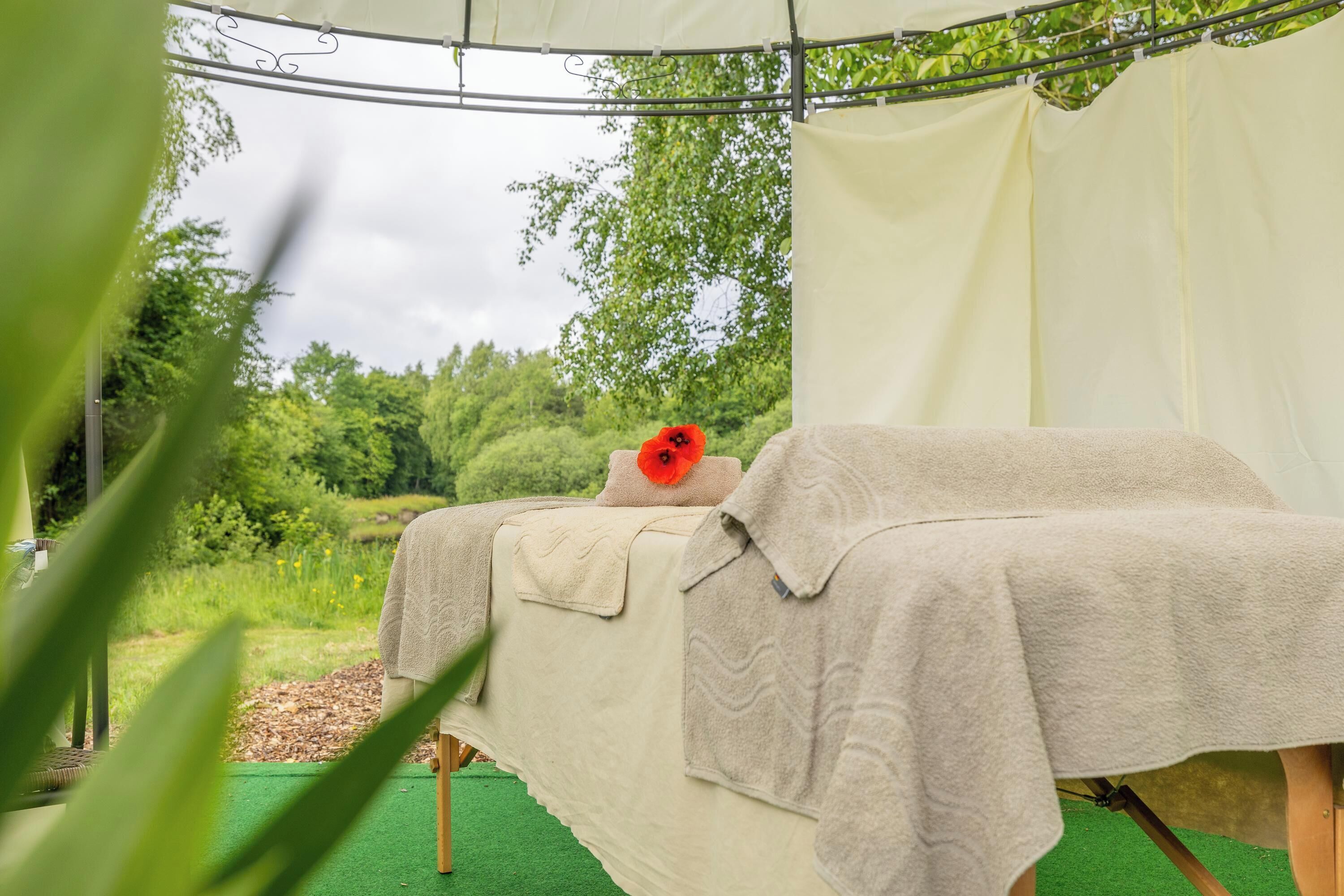 A spa bed with a poppy flower, a towel, and a canopy.
