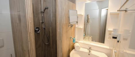 Un baño moderno con cabina de ducha de madera, un lavabo blanco y un espejo sobre él.
