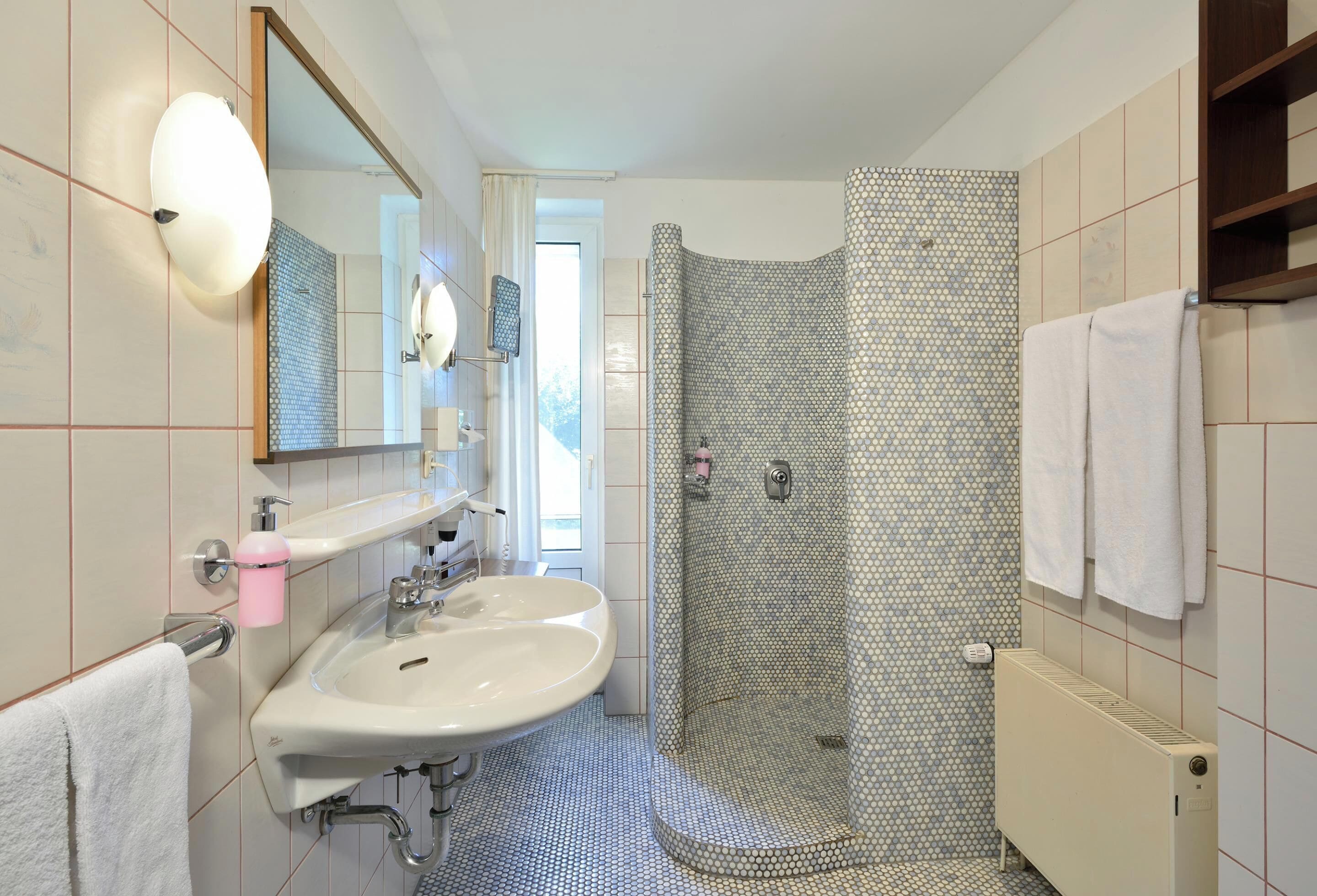 Une salle de bain moderne avec un grand lavabo, un miroir, une cabine de douche et un porte-serviettes.