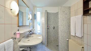 Une salle de bain moderne avec un grand lavabo, un miroir, une cabine de douche et un porte-serviettes.