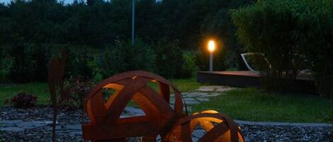 A garden with two large metal spheres and a street lamp.