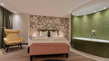Ein modernes Schlafzimmer mit einem großen Bett, einer Chaiselongue und einer grün gefliesten Duschwand.
