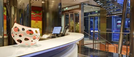 A modern reception area with a curved counter, a laptop, and a decorative bowl.