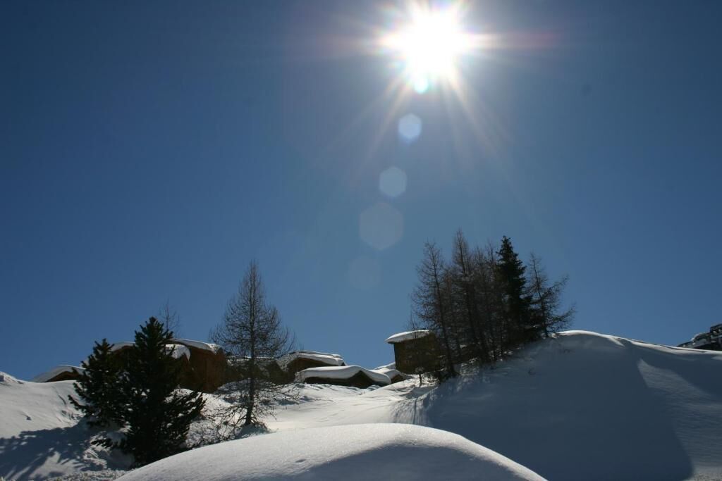 Schneegebirgslage mit blauem Himmel und hell scheinender Sonne.