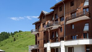 Un immeuble en bois à plusieurs étages, doté de balcons, qui se dresse sur une colline verdoyante.