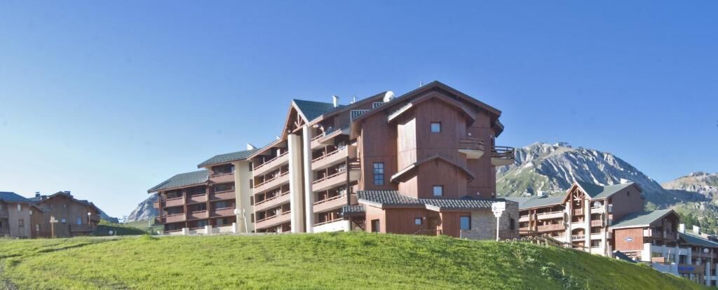 Un hôtel à plusieurs étages, doté de balcons, situé dans un cadre montagneux.