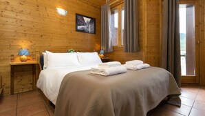 Une chambre dans une cabane en bois, avec un lit, des tables de chevet et une fenêtre avec des rideaux.