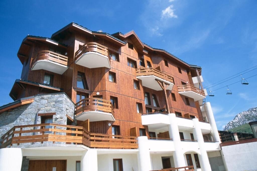 A multi-story hotel with wooden balconies and a stone facade.