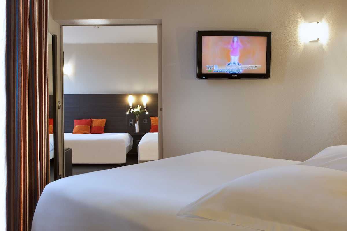 Habitación de hotel con una cama grande, un televisor montado en la pared y una mesita con dos lámparas.