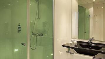 A modern bathroom with a glass shower enclosure, a black sink, and a mirror.