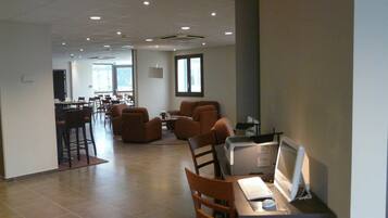 Un vaste espace intérieur aménagé avec différents types de sièges, notamment des canapés et des fauteuils, ainsi qu’un poste de travail informatique.