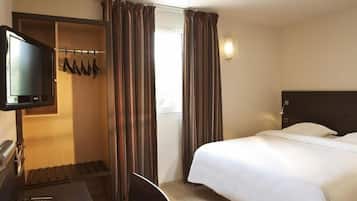 Ein Hotelzimmer mit einem Bett, einem Schreibtisch mit Fernseher, einem Schuhregal und Vorhängen.
