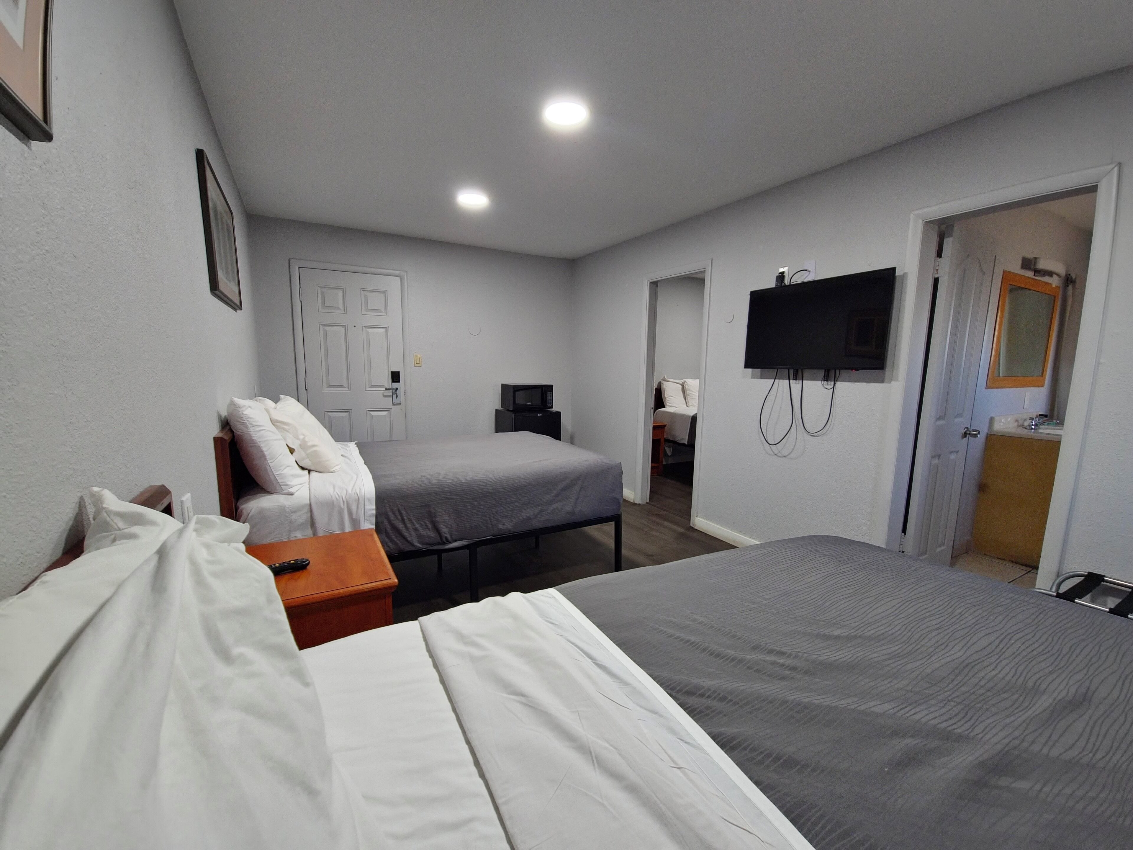 A hotel room with two beds, a TV mounted on the wall, and a door leading to a bathroom.