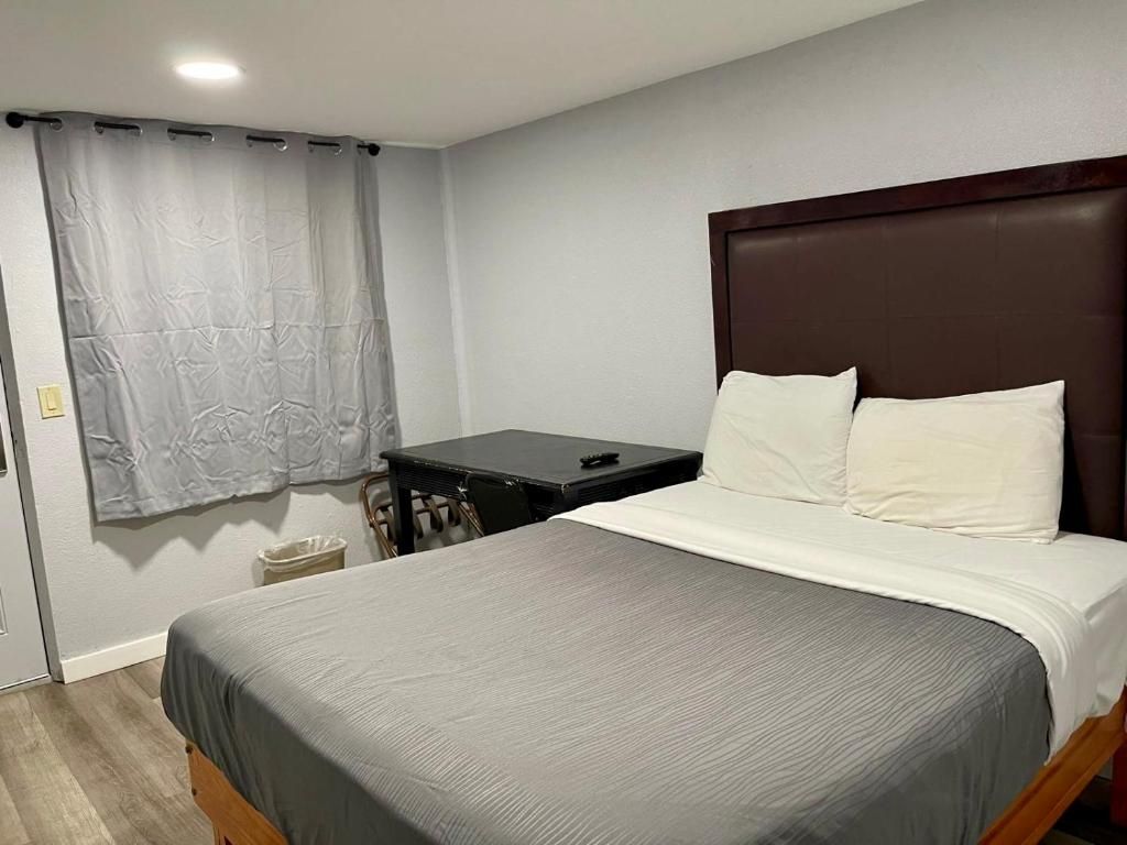 A bedroom with a bed, a bedside table, and a curtain.